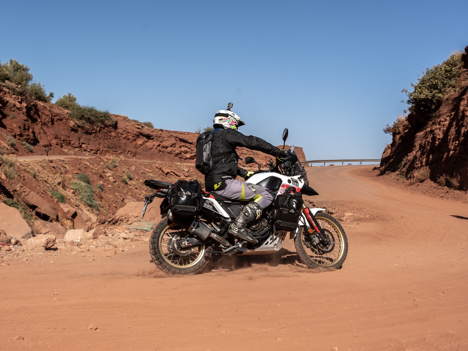 Moto soulevant la poussière sur une route de montagne marocaine
